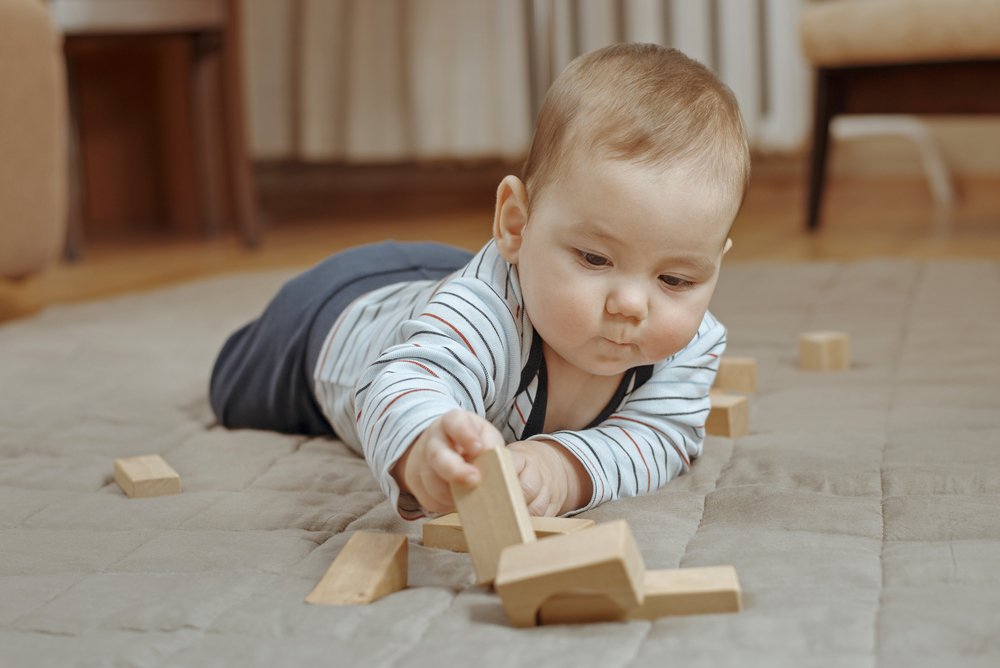 Tummy time baby playing with wooden toy